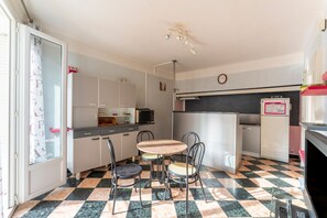 A compact kitchen with a checkered floor, a small dining table, and metal chairs.