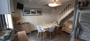 A dining area with a table and chairs, a staircase, and a wall-mounted television. - Holiday Home 'Résidence Clos De Tamaris' with Shared Pool, Private Terrace and Air Conditioning (Marseillan)
