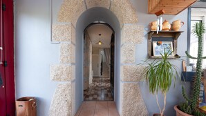 An arched doorway leading to a tiled hallway with a potted plant and a cactus on the right.