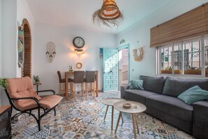 A living room with a sofa, chairs, a coffee table, a patterned floor, a wall clock, and a door with a geometric design. - Holiday Home 'Gecko' with Private Terrace, Wi-Fi and Air Conditioning (Benalmádena)