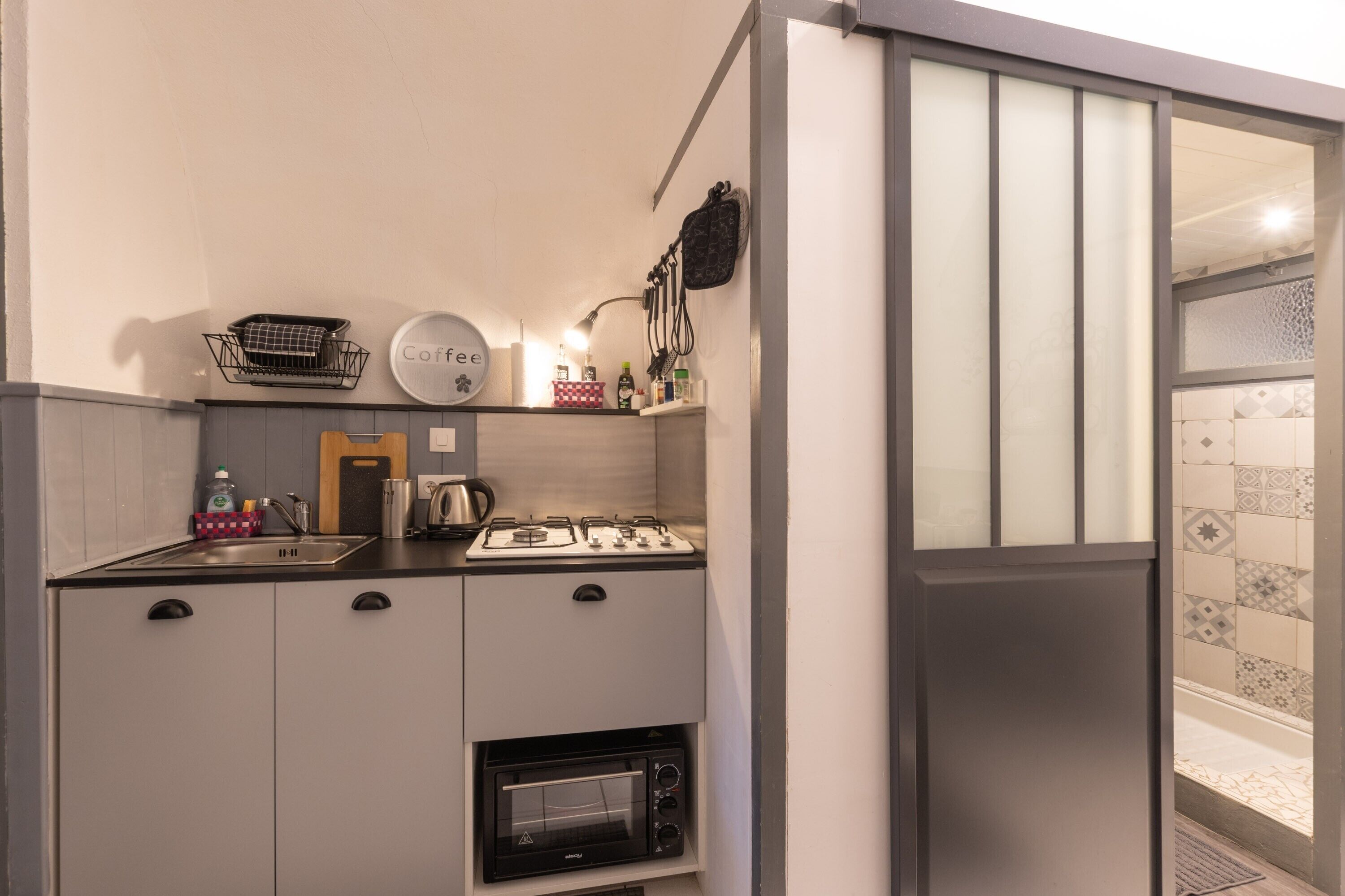 A compact kitchen with a built-in oven, a coffee station, and a small sink.