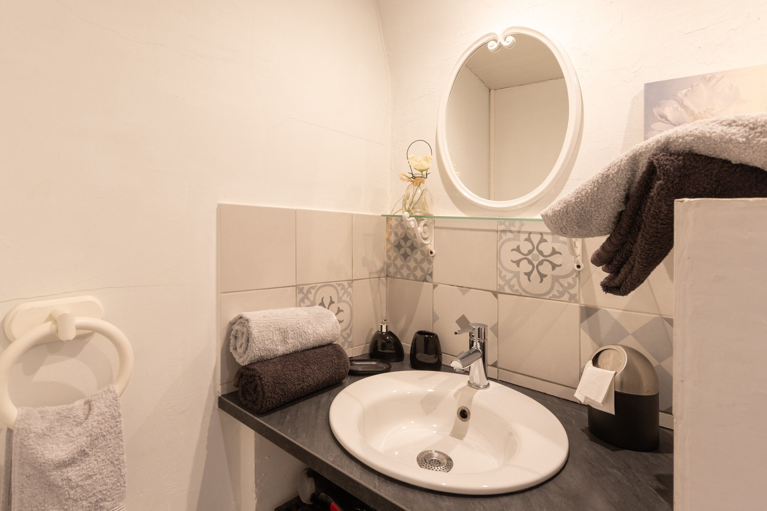 A bathroom with a white sink, a mirror, a towel rack, and a towel dispenser.