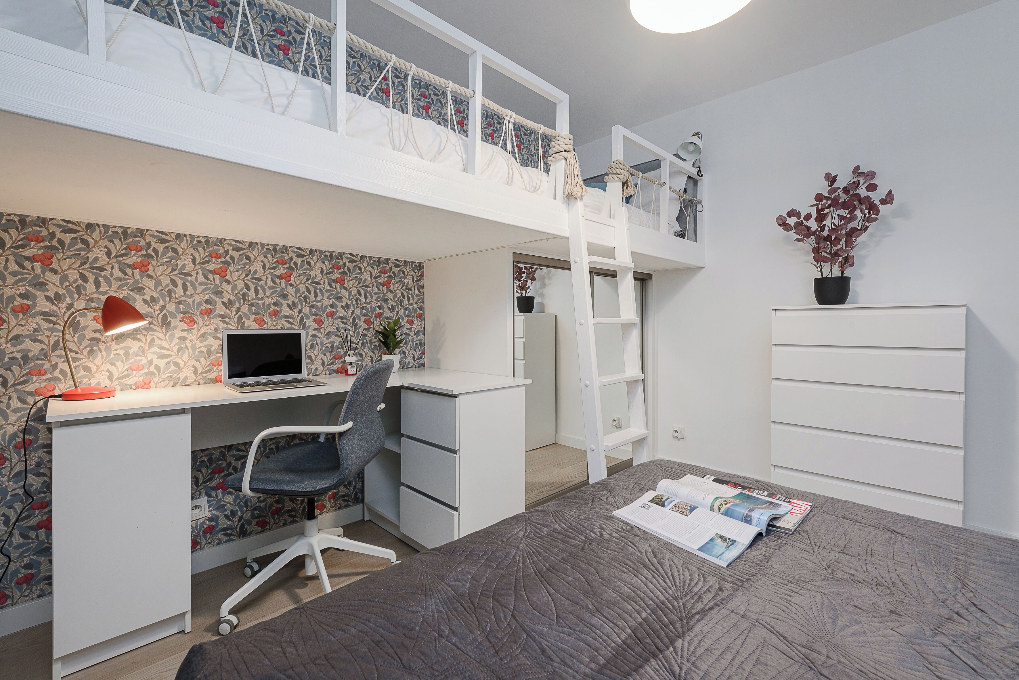 A bedroom with a loft bed, a desk with a computer, a chair, and a ladder.