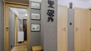 A hallway with a wooden door, a small wooden stool, and three framed pictures on the wall. - Lumina apartment in center Warsaw (Warsaw)