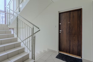 Staircase with a modern design, featuring a handrail and white steps, adjacent to a door with a dark finish.