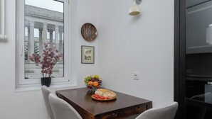 A dining area with a wooden table, two chairs, a bowl of fruit, and a loaf of bread. - Lumina apartment in center Warsaw (Warsaw)
