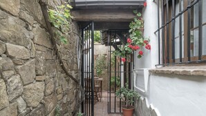 Un mur de pierre, une table en bois, une plante en pot et une fenêtre donnant sur un beau paysage.