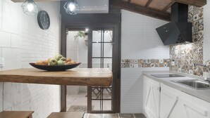Une cuisine avec un plan de travail en bois, un saladier rempli de fruits, un évier et un crédence décorée.