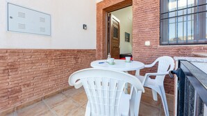 A patio area with a brick wall, a white table with chairs, and a window.