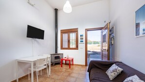 A room with a bed, a TV, a small table, a chair, a heater, and a window.