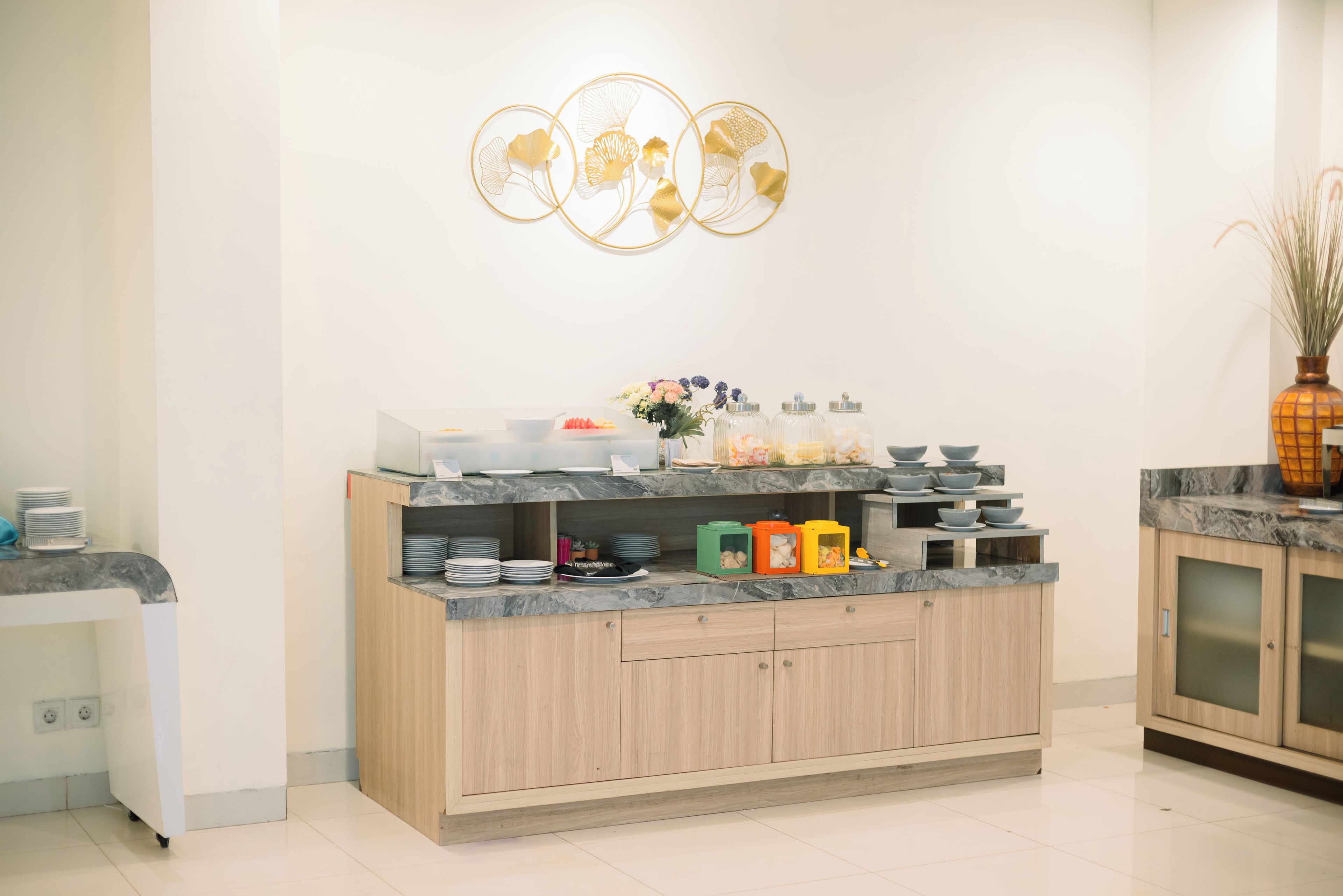 A modern kitchen with a marble countertop, wooden cabinets, and a decorative wall piece above the counter.