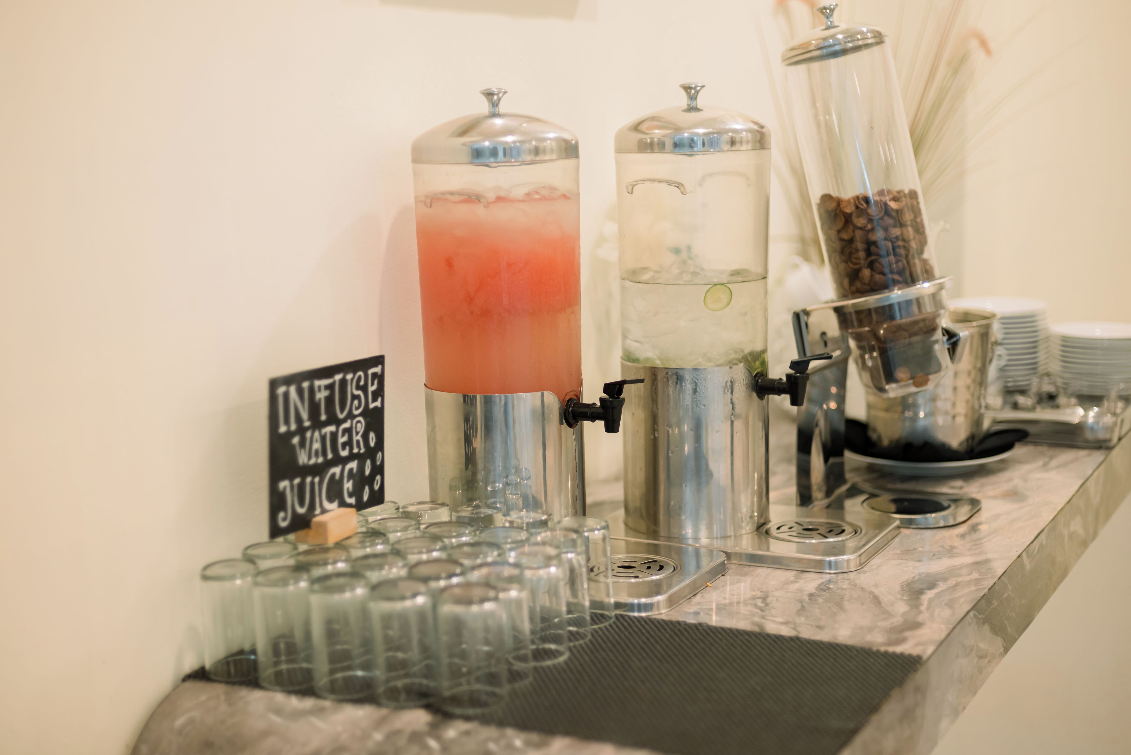 Una estación de bebidas con dispensadores de agua y jugo, y un letrero que indica la disponibilidad de agua y jugo saborizados.