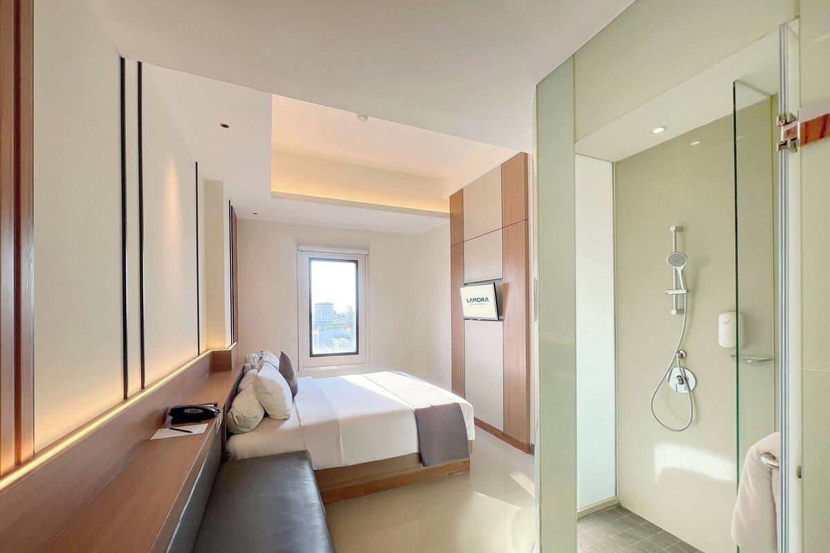Une chambre d’hôtel moderne équipée d’un lit, d’une banquette et d’un espace douche.
