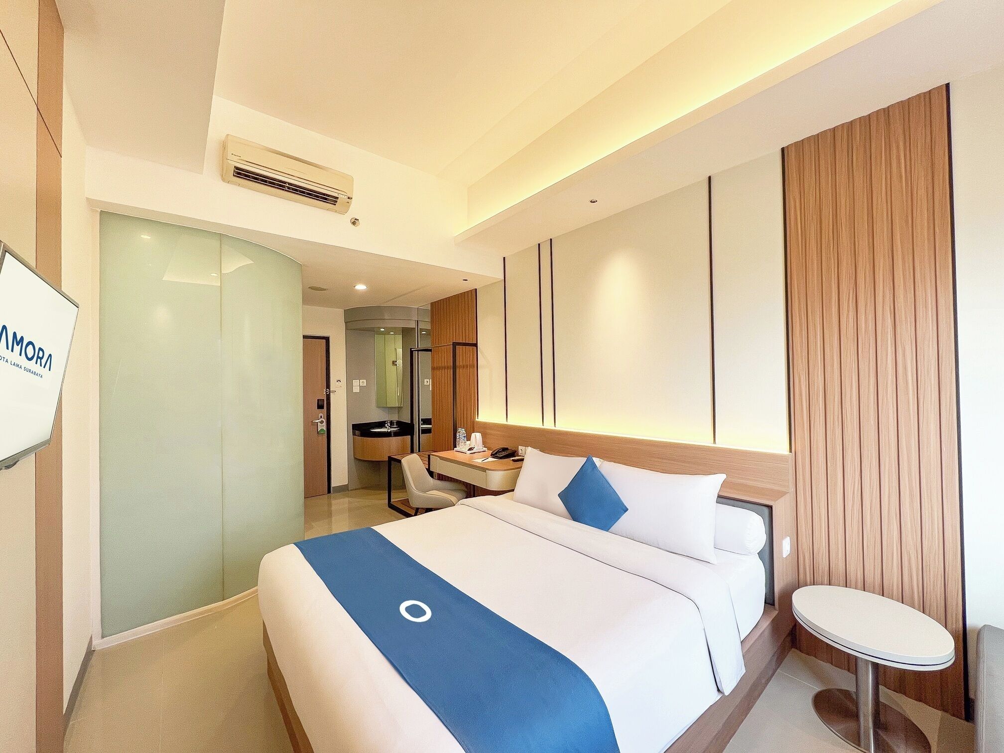 A hotel room with a bed, a desk, a chair, and a small table.