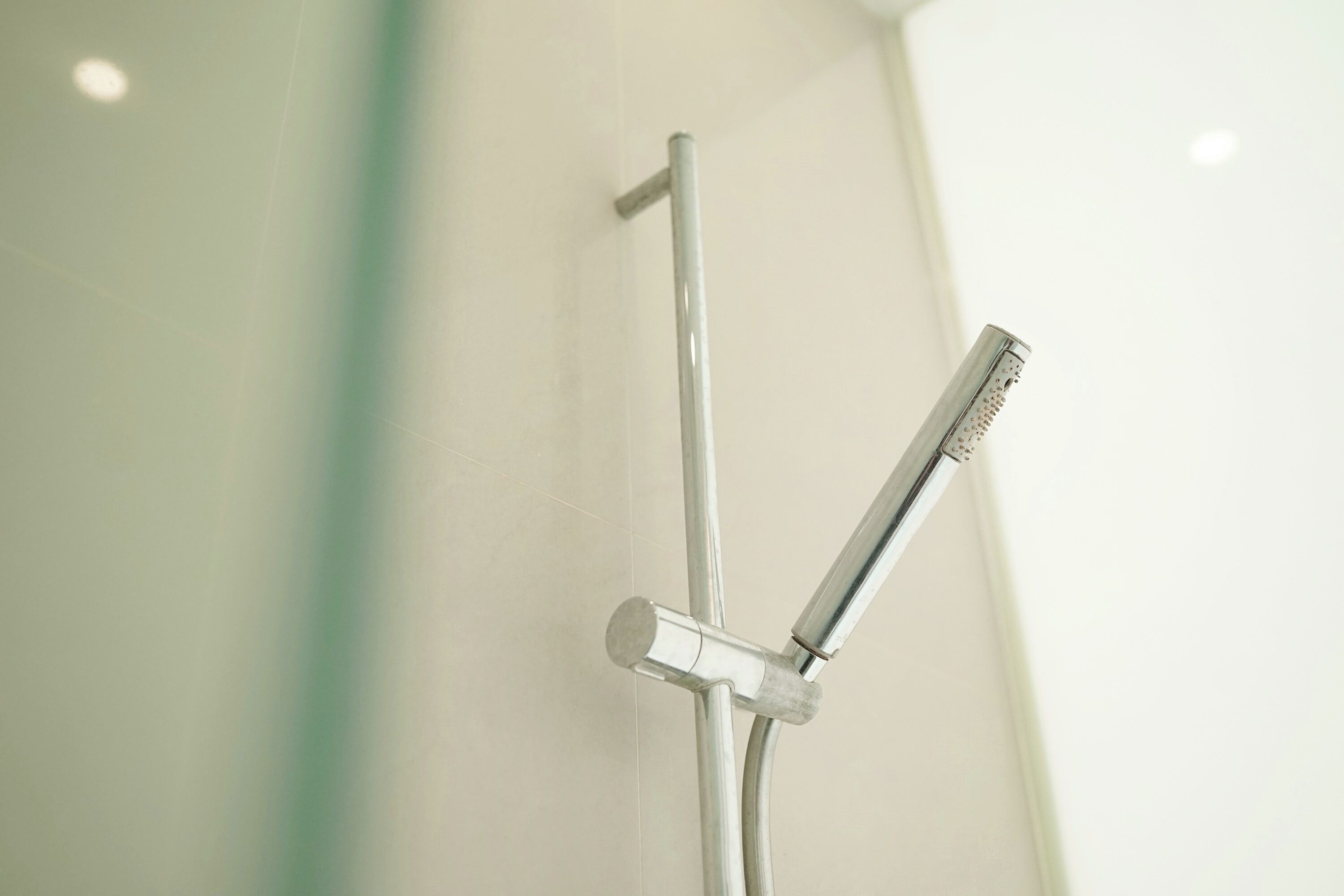 Een moderne douche met een handdouche en een vaste muurkraan.
