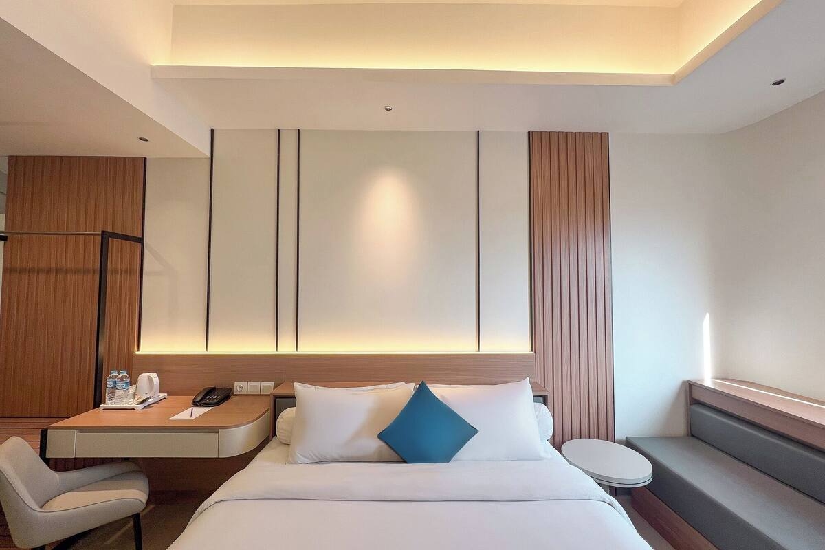 Une chambre d’hôtel moderne équipée d’un lit, d’un bureau, d’une chaise et d’une petite table.
