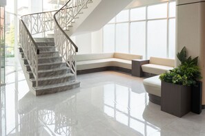 Un intérieur moderne avec un escalier en marbre, un canapé blanc aux lignes courbes et une plante en pot.