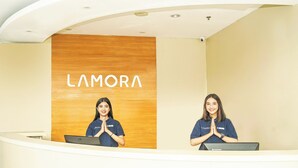 Een receptiegedeelte met een houten wand waarop de tekst 'LAMORA' staat.