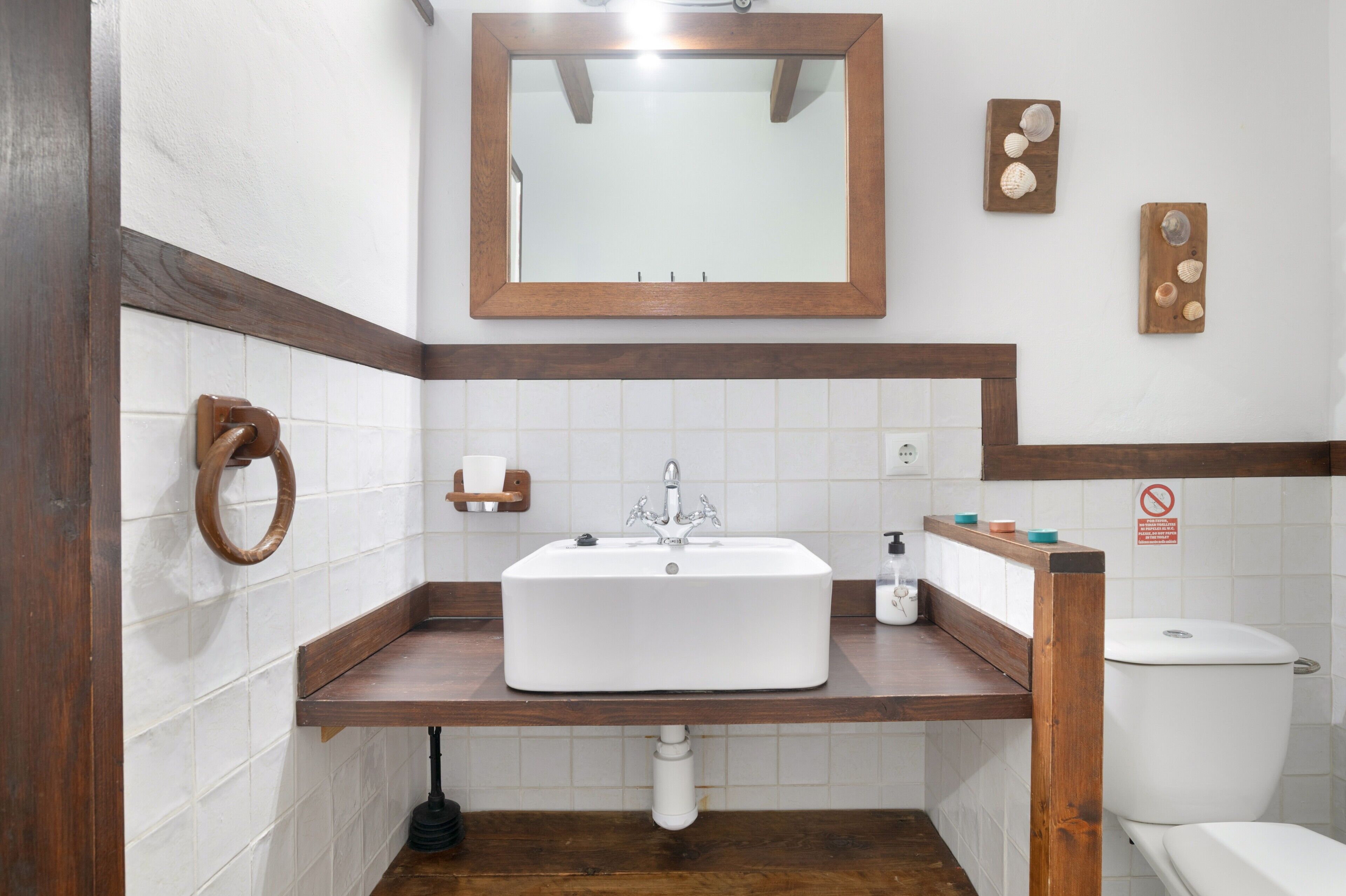A bathroom with a wooden vanity, white sink, and a mirror above it.