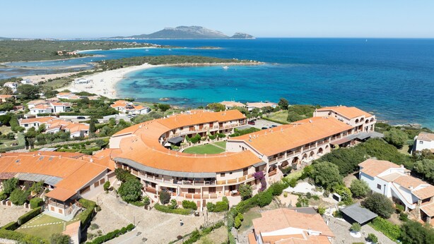 A coastal resort with terracotta-roofed buildings, a beachfront, and a clear view of the sea and distant mountains. - Mishti Blu Studio al Mare by Wonderful Italy (Olbia)