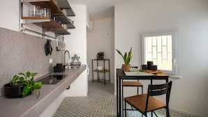 A modern kitchen with built-in shelves, a countertop with a sink, and a dining area with a table and chairs. - Casa di Design tra le Mura by Wonderful Italy (Palermo)