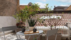 An outdoor patio area with a round table, two chairs, potted plants, and a view of buildings in the background. - Casa di Design tra le Mura by Wonderful Italy (Palermo)