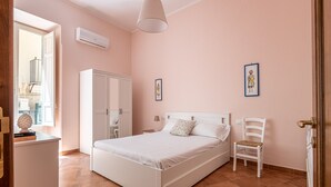 A bedroom with a bed, a chair, a wardrobe, and a window. - Il Cortile Degli Aragonesi by Wonderful Italy (Palermo)