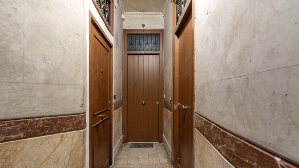 A narrow hallway with marble walls, wooden doors, and a patterned rug on the floor. - Il Cortile Degli Aragonesi by Wonderful Italy (Palermo)