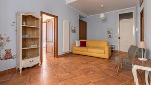 A living room with a yellow sofa, a wooden cabinet, and a patterned chair. - Il Cortile Degli Aragonesi by Wonderful Italy (Palermo)