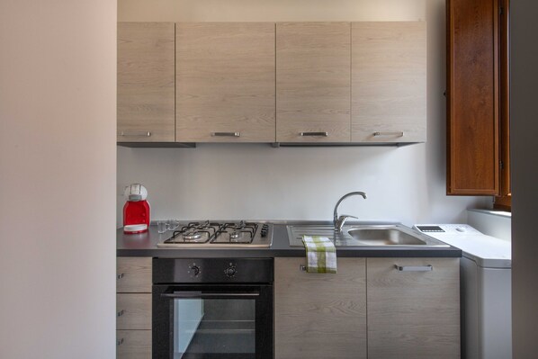 A modern kitchen with light wood cabinets, a gas stove, a built-in oven, a sink, and a red coffee maker. - Dimora Umberto I by Wonderful Italy (Cefalù)