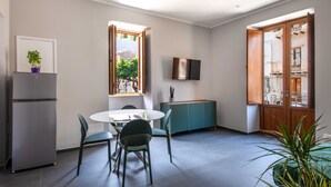 Una cucina moderna con tavolo da pranzo, sedie, frigorifero, televisione e finestra vista esterna.