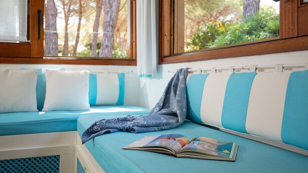 Una habitación acogedora con una cama, una ventana que da a árboles y una mesita con un libro.