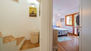 Ein Zimmer mit einem Bett, einem Fenster, einer Tür und einer Treppe.