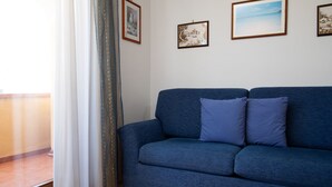 A room with a blue sofa, a curtain, and three framed pictures on the wall.