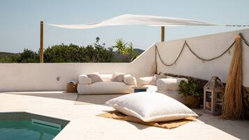 Terraza en la azotea con piscina, sofá blanco y un farol colgante.
