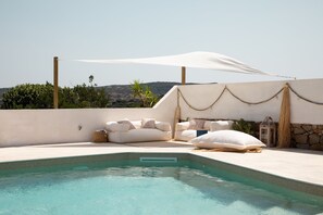 A pool area with a white canopy, beige cushions, and a stone wall. - Villa Erma by Wonderful Italy (Santa Teresa di Gallura)