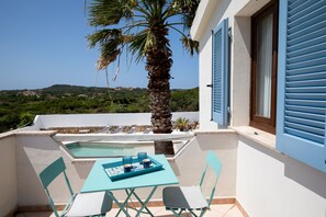 A balcony with a pool, a palm tree, and a table with chairs. - Villa Erma by Wonderful Italy (Santa Teresa di Gallura)