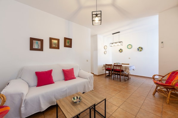 A living room with a sofa, a dining table with chairs, and a small table with a bowl.