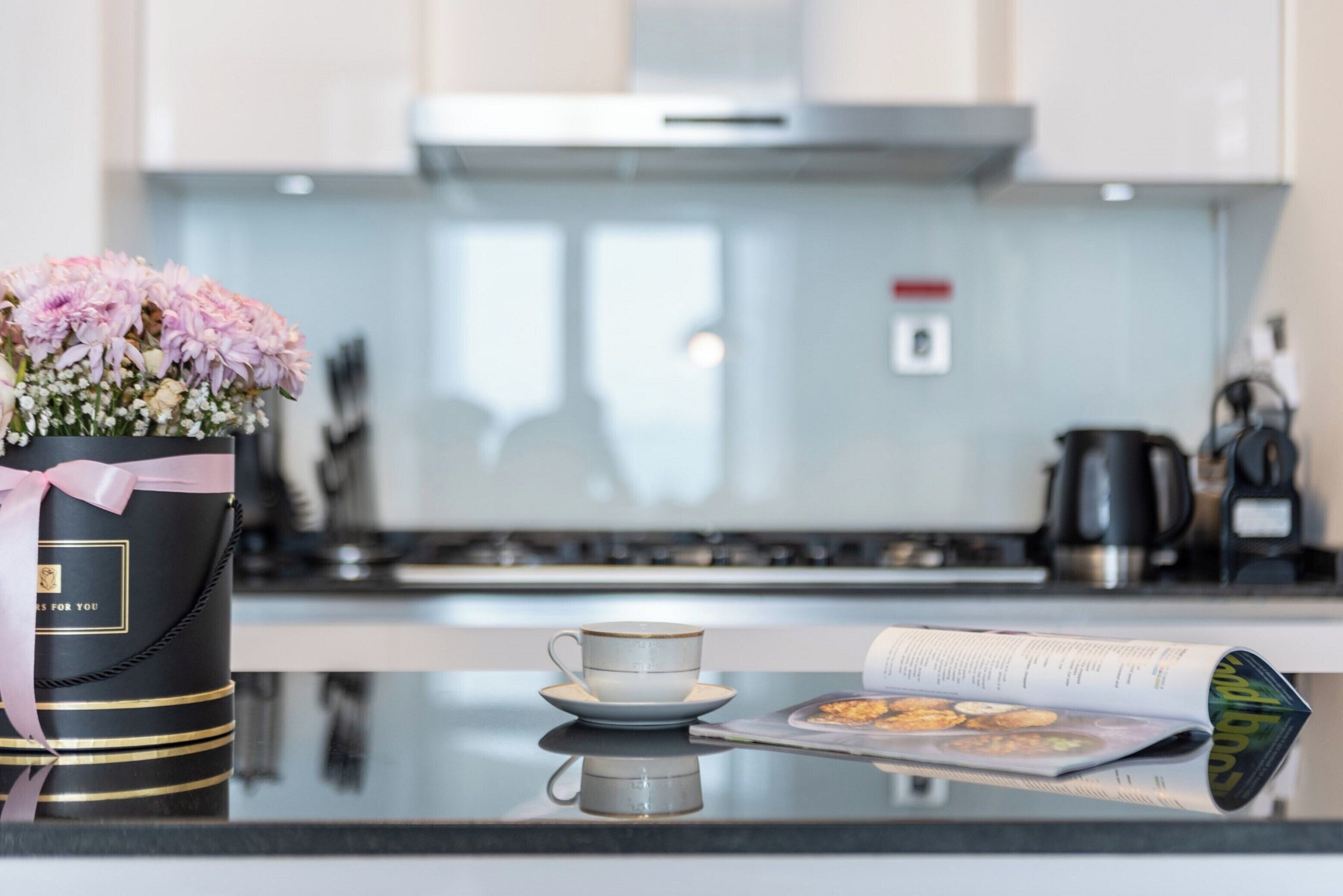 A kitchen with a black gift basket, a cup, and a magazine on the counter.