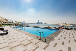 Una piscina al aire libre, sombrillas, tumbonas