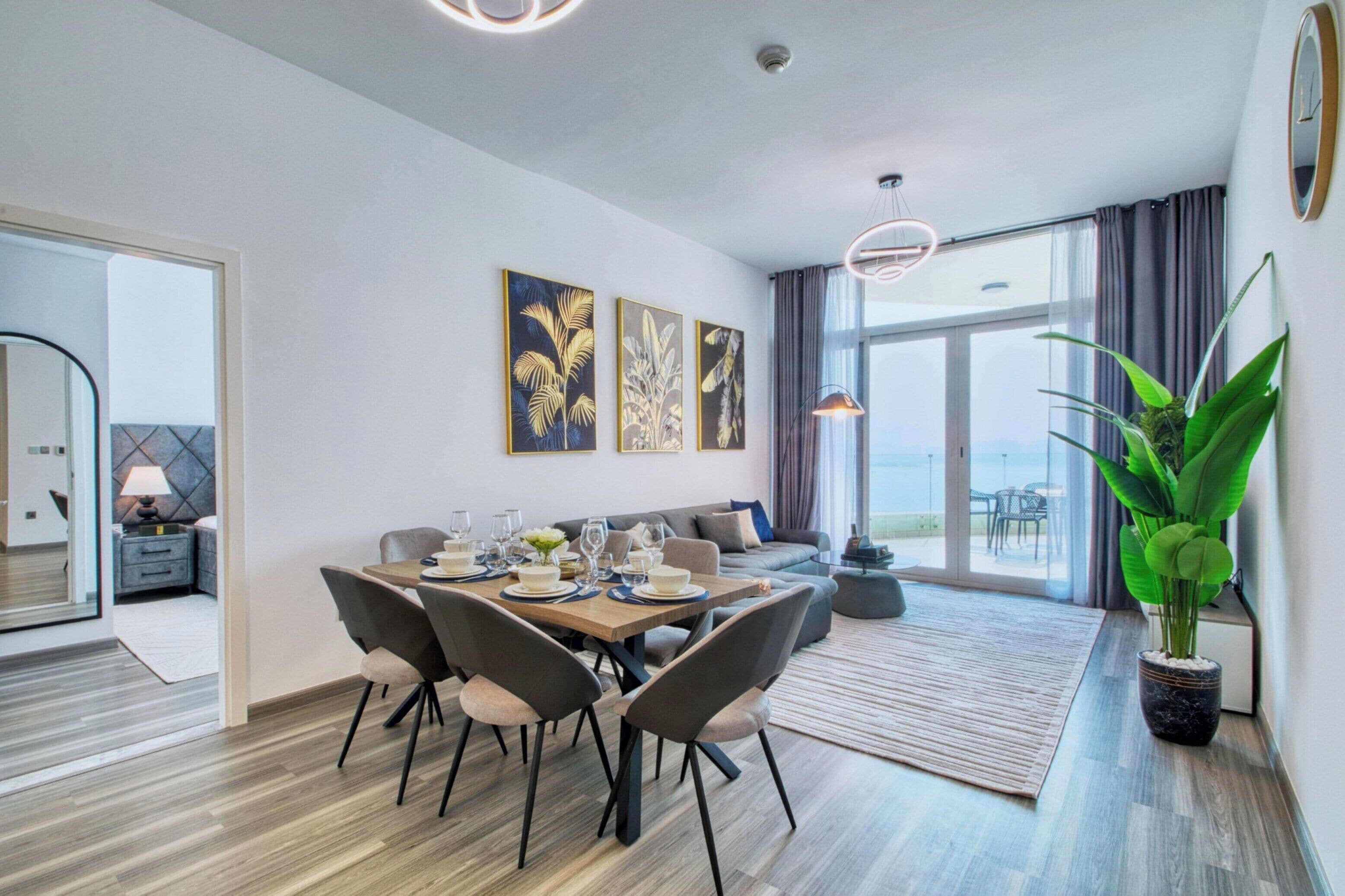 Una sala de estar moderna con comedor, ventanas amplias y vista al mar.