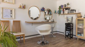 A salon with two wooden chairs, a white salon chair, and a black cart. - Room in Studio - Nice Studio on Jasmine (Bomaderry)