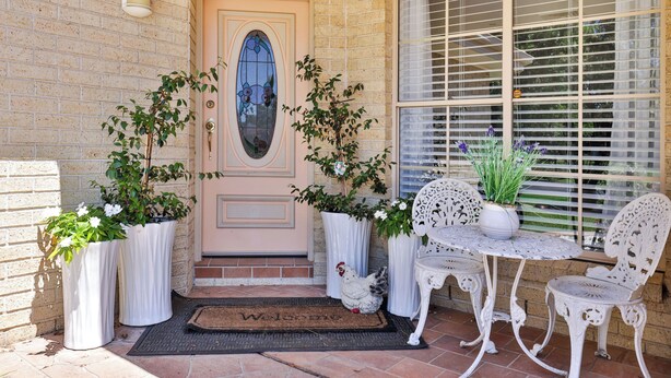 A front porch with a welcome mat, potted plants, and white outdoor furniture. - Room in Studio - Nice Studio on Jasmine (Bomaderry)