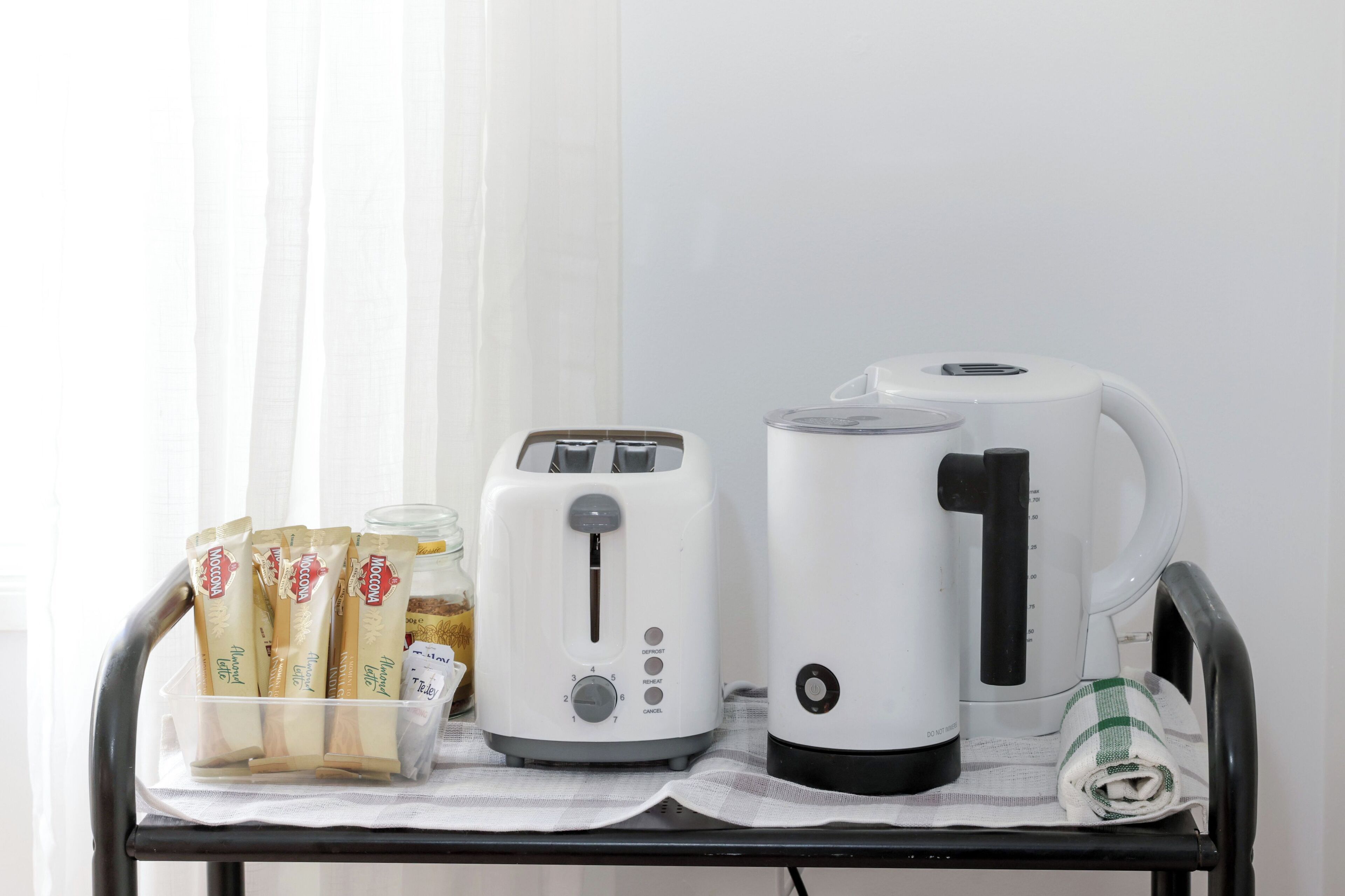 A kitchen counter with a toaster, a kettle, and a container of bread.