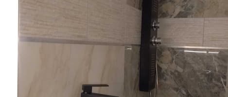A bathroom with a white sink, a black faucet, and a marble-tiled wall.