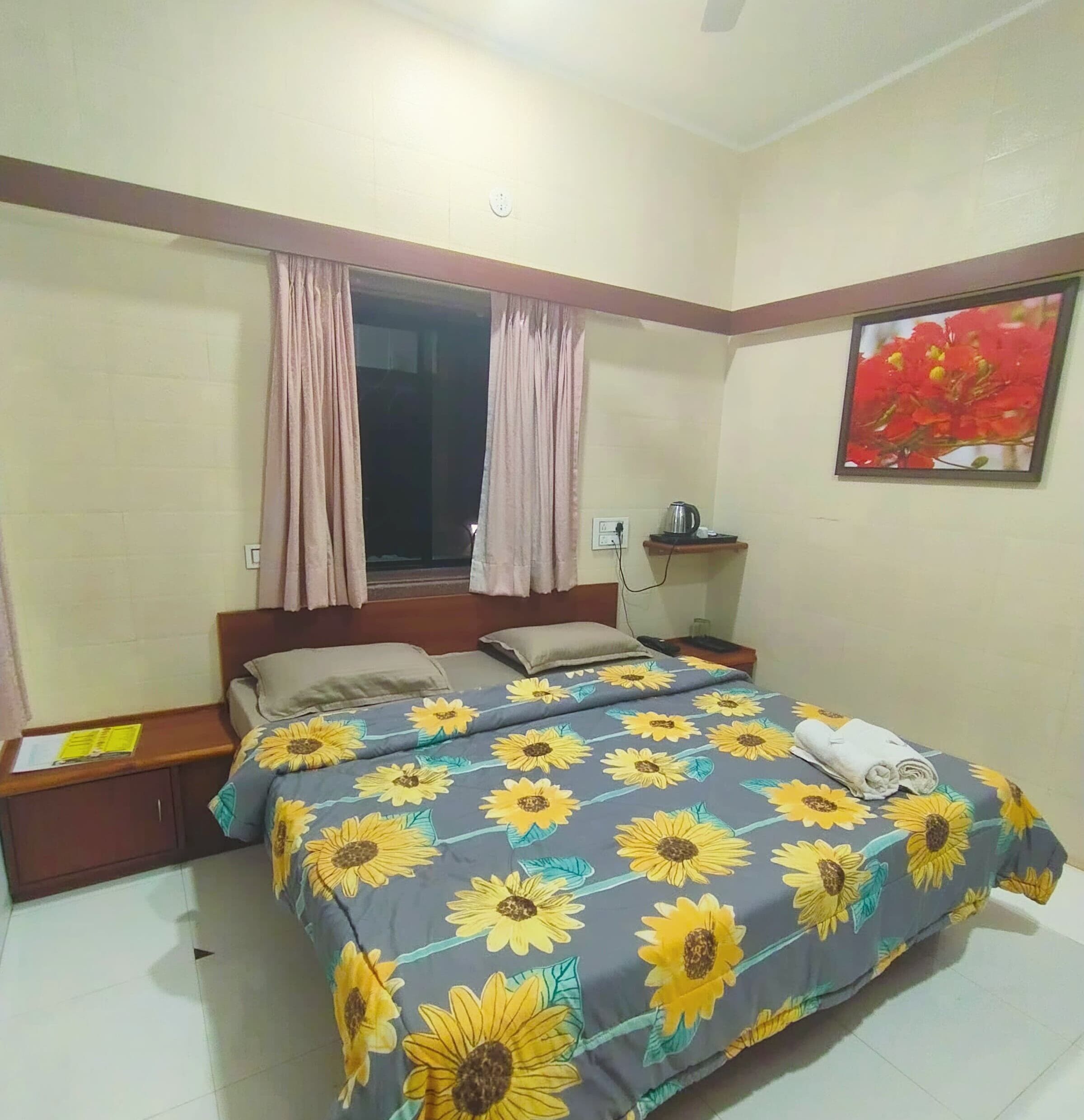 A bedroom with a bed, two nightstands, a window with curtains, a wall-mounted shelf, and a painting.