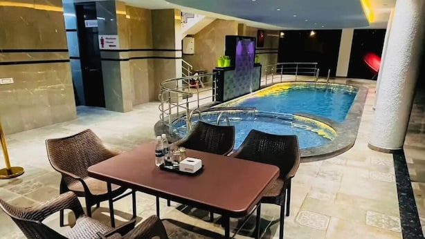 Zona de piscina interior con mesa y sillas, una escalera y un bar junto a la piscina.