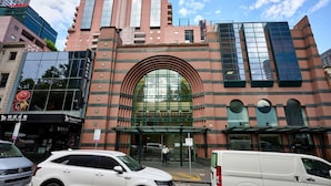 A modern building with a large arched entrance, glass windows, and a parking area in front. - Exhibition Street Retreat - Central Stay with Parking (Melbourne)