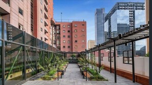 A modern urban courtyard with a glass facade, a central pathway, and surrounding greenery. - Exhibition Street Retreat - Central Stay with Parking (Melbourne)