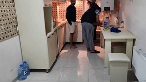 Une cuisine compacte avec des meubles blancs, un petit plan de travail et une fenêtre au-dessus de l’évier.